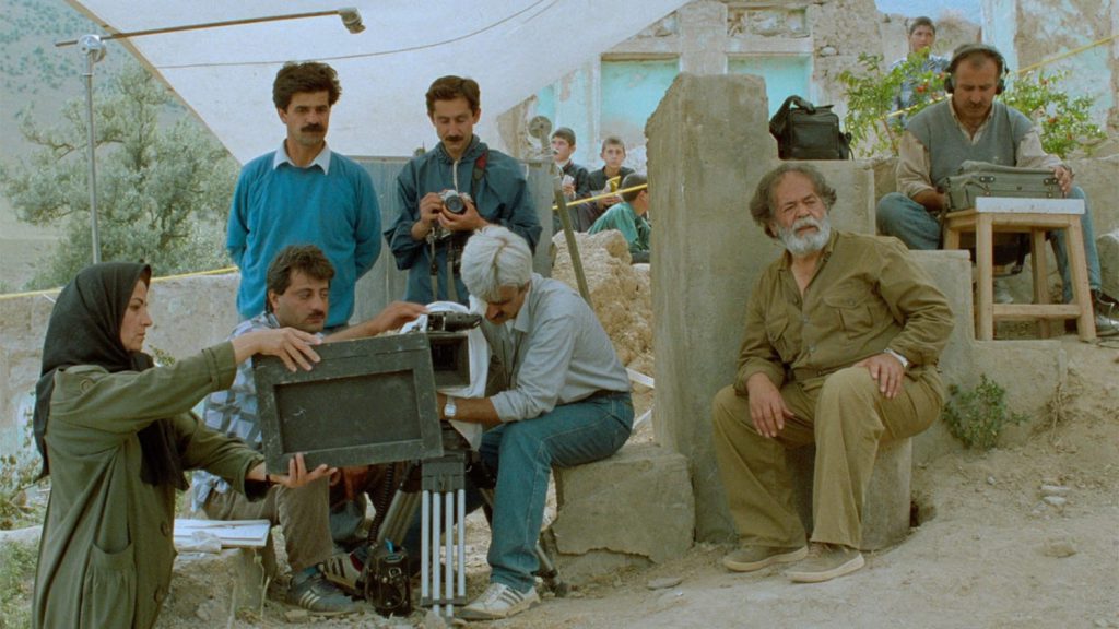 Från filmen under olivträden (1994), Abbas Kiarostami. Janus Films. Flera personer på en filminspelning med kameror och mikrofoner.