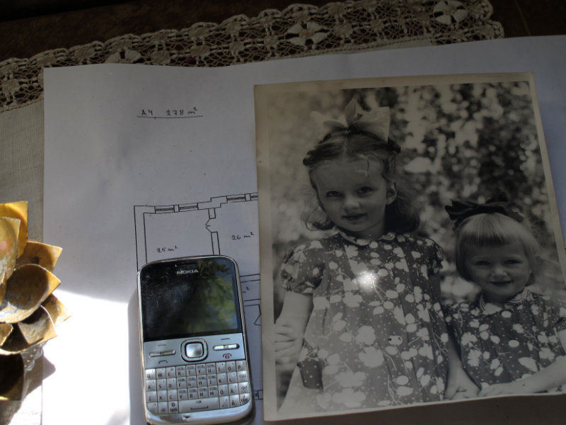 Stillbild på en äldra mobiltelefon och ett kort på två barn ur filmen "Till minne av ett hem". Foto: Helena Öst.